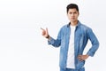 Portrait of serious-looking angry young asian guy scolding person for making big mistake, pointing finger left at Royalty Free Stock Photo