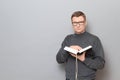 Portrait of serious man with glasses holding open big book in hands