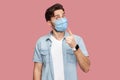 Portrait of serious man with surgical medical mask in blue casual style shirt standing with warming sign and looking at camera to Royalty Free Stock Photo