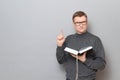 Portrait of serious mature man holding open book and raising finger up