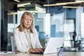 Portrait of serious mature thinking businesswoman, gray haired female boss looking at camera, at workplace inside office