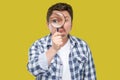 Portrait of serious middle aged man in casual checkered shirt standing, holding magnifying glass and looking at camera with big Royalty Free Stock Photo