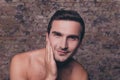 Portrait of serious naked young man after shower touching his face Royalty Free Stock Photo