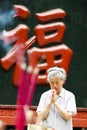 Portrait of serious old caucasian woman praying Buddha