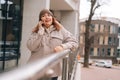 Portrait of serious overweight woman in warm hat and jacket talking on mobile phone standing near railing at city street Royalty Free Stock Photo