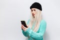 Portrait of serious pretty blonde girl looking in smartphone on white background. Royalty Free Stock Photo