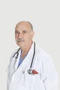 Portrait of serious senior medical practitioner over gray background