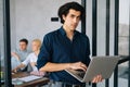 Portrait of serious startup businessman in casual clothes holding laptop in hand standing in office room, confident Royalty Free Stock Photo