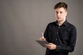 Portrait of serious stylish attractive man dressed with a casual black shirt taking notes looking at the camera Royalty Free Stock Photo