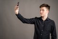 Portrait of serious stylish attractive man dressed with a casual black shirt taking selfie photo Royalty Free Stock Photo