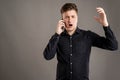 Portrait of serious stylish attractive man dressed with a casual black shirt talking on the phone, gesturing angry face Royalty Free Stock Photo