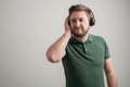 Portrait of serious stylish attractive man with thick beard, dressed in casual green t shirt listen good music Royalty Free Stock Photo