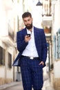 Serious stylish businessman walking in city street Royalty Free Stock Photo