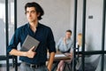 Portrait of serious team leader holding in hand stylish paper notebook standing in modern office room , pensive looking Royalty Free Stock Photo