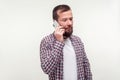 Portrait of serious upset bearded man talking on cell phone, looking aside with gloomy dismal face. white background Royalty Free Stock Photo