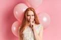 Upset redhaired girl in white wedding dress with air balloons