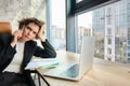 Portrait of serious woman having negotiation over the phone. Businesswoman with smartphone, looking at laptop screen Royalty Free Stock Photo