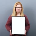 Portrait of serious woman holding blank sign board.Studio portrait of young woman with sign card against gray background Royalty Free Stock Photo