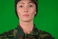 Portrait of a serious woman in military uniform. Violation of gender stereotype. Green background