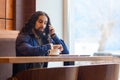 Portrait of serious worry handsome young adult man freelancer in casual style sitting in cafe, talking on the phone and looking to Royalty Free Stock Photo