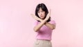 portrait serious young asian woman with cross arm gesture showing stop, no, wrong, denial, rejection sign  on pink pastel Royalty Free Stock Photo