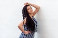 Portrait of serious young brunette woman with black afro american dreadlocks hairstyle in striped dress posing and looking at Royalty Free Stock Photo