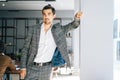 Portrait of serious young business man wearing fashion suit standing near window in modern office room, looking at Royalty Free Stock Photo