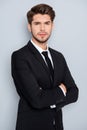 Portrait of serious young businessman in black suit with crosed hands