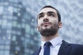 Portrait of serious young businessman looking up, outdoors, business district Royalty Free Stock Photo