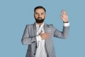 Portrait of serious young congressman taking oath on blue studio background