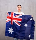 Portrait of serious young female holding national flag of Australia against gray wall Royalty Free Stock Photo