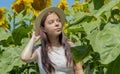 Portrait of a serious young girl of 17-20 years old in a straw hat against a background of blooming sunflowers. Photo shoot agains