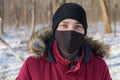 Portrait of a serious young man wearing a black protective mask. Looks calmly in front of him. Copyspace for text