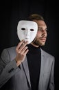 Portrait of a serious young man holding a white mask in his hand, concept for being authentic Royalty Free Stock Photo