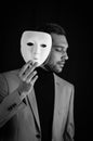 Portrait of a serious young man holding a white mask in his hand, concept for being authentic Royalty Free Stock Photo