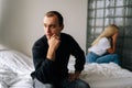 Portrait of serious young man pensive looking away not talking after dispute with sad wife sitting apart on bed Royalty Free Stock Photo