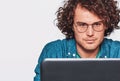 Portrait of serious young man sitting at his desk with laptop. Closeup image of Caucasian businessman working in office