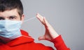 Portrait of serious young pulled gum on medical mask on face on gray studio background, person ready to fight epidemic, quarantine Royalty Free Stock Photo