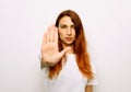 Portrait of a serious young redhair woman standing with outstretched hand showing stop gesture Royalty Free Stock Photo