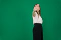 Portrait of a serious young woman standing with outstretched hand showing stop gesture isolated over green background Royalty Free Stock Photo