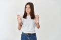 Portrait of a serious young woman standing with outstretched hand showing stop gesture isolated over white background Royalty Free Stock Photo