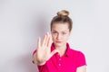 Portrait of a serious young womanin in pink dress standing with outstretched hand showing stop gesture over white background. Body Royalty Free Stock Photo