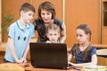 Portrait of several kids and their teacher looking at laptop screen in classroom Royalty Free Stock Photo