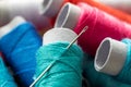A portrait of a sewing needle stuck in a roll of thread. The spool of wire is lying on top of others rolls, all of them have a Royalty Free Stock Photo