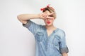 Portrait of sexual beautiful young woman in casual blue denim shirt with makeup and red headband standing, showing victory v sing Royalty Free Stock Photo