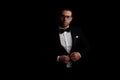Portrait of sexy arabic man with glasses adjusting and buttoning black tuxedo Royalty Free Stock Photo