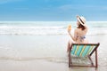 Portrait of sexy asian young girl in bikini and hat sitting on deck chair at tropical beach and holding orange juice with beauty Royalty Free Stock Photo