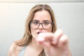 Blonde girl with glasses in a hotel eating a candy. Royalty Free Stock Photo