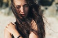 Portrait of brunette model in knitted sweater posing on the sandy beach, big stones and rock on background. Royalty Free Stock Photo