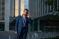 Portrait sexy businessman using smartphone near modern building outdoor. Successful business man walking in suit at Royalty Free Stock Photo